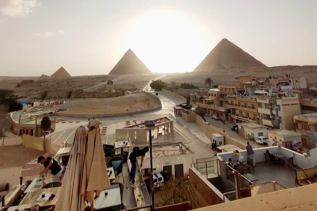 해가 지고 도로가 이어지는 세 개의 피라미드는 건물과 테라스가 사람들과 마주하고 있습니다.