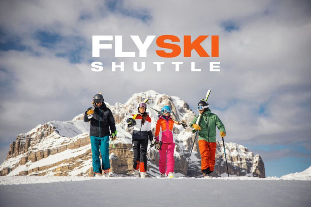 위에 "Fly Ski Shuttle" 문구가 있는 설산 풍경을 걷는 스키 장비를 입은 네 명의 사람들.