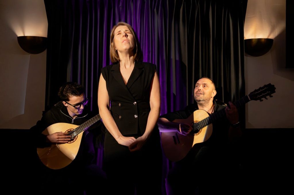 보라색 커튼이 드리워진 희미한 무대에서 두 명의 기타리스트가 눈을 감고 노래를 부릅니다.