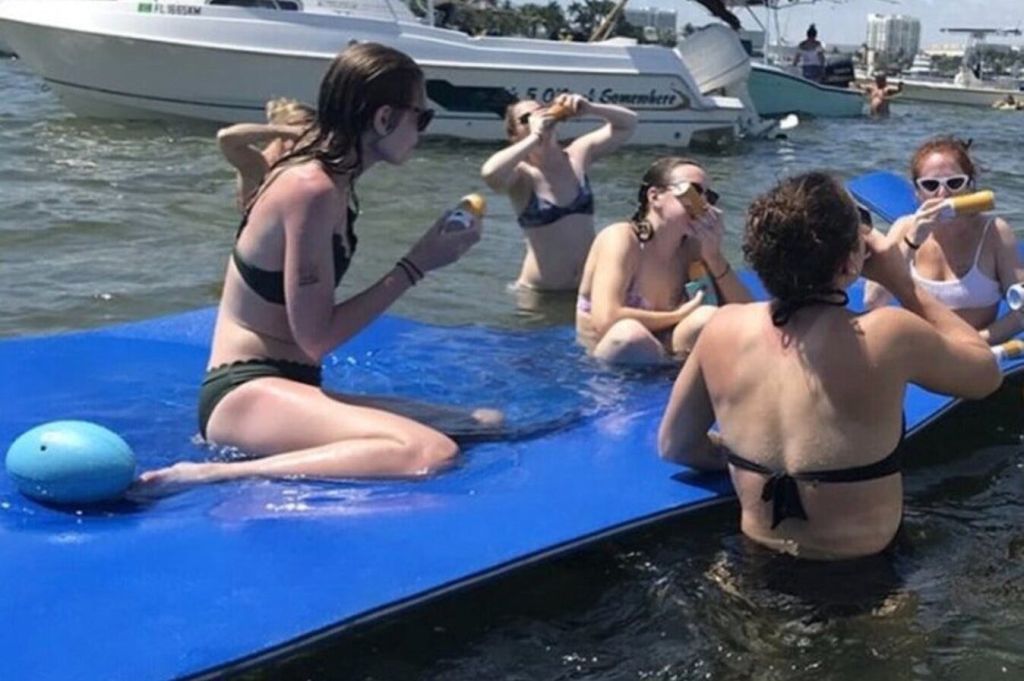 Amigos comparten risas y disfrutan de bebidas animadas: una imagen vibrante de amistad despreocupada en el agua.