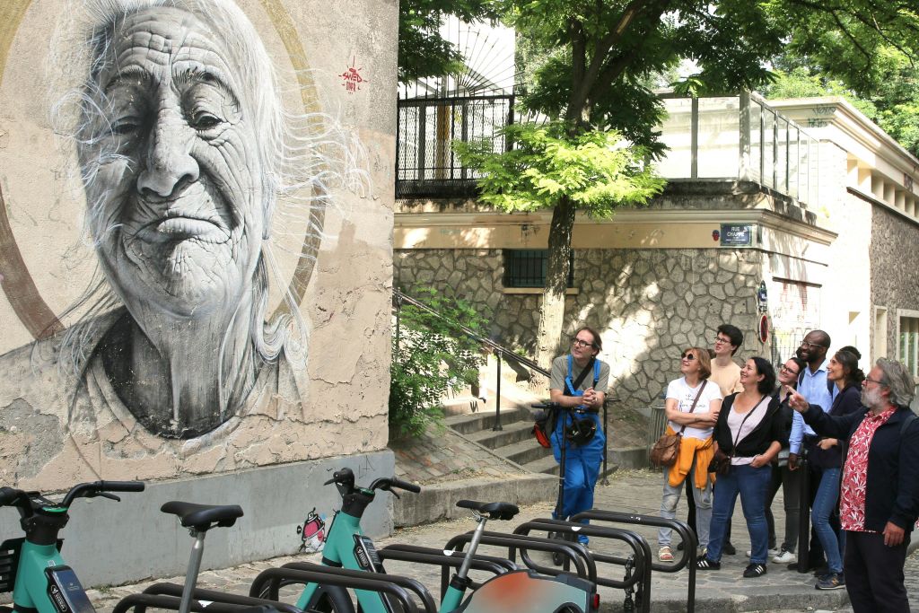 몽마르트르의 대형 벽화를 단체로 보여주는 가이드.