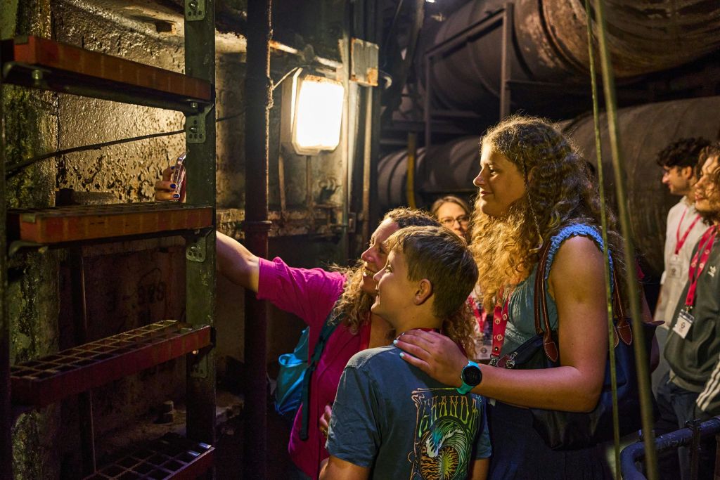 벽이나 장비를 중심으로 커다란 파이프와 희미한 조명이 있는 인더스트리얼 스타일의 인테리어를 살펴보는 사람들의 모임.