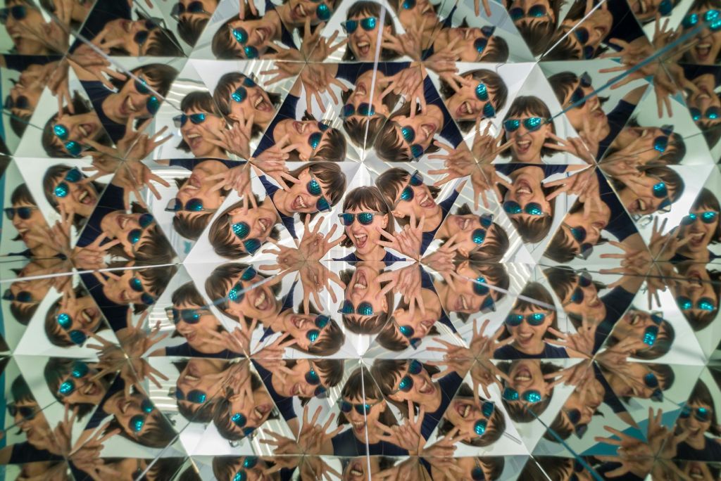 만화경 효과로 파란색 선글라스를 착용하고 애니메이션 손짓을 하는 사람의 여러 반사.