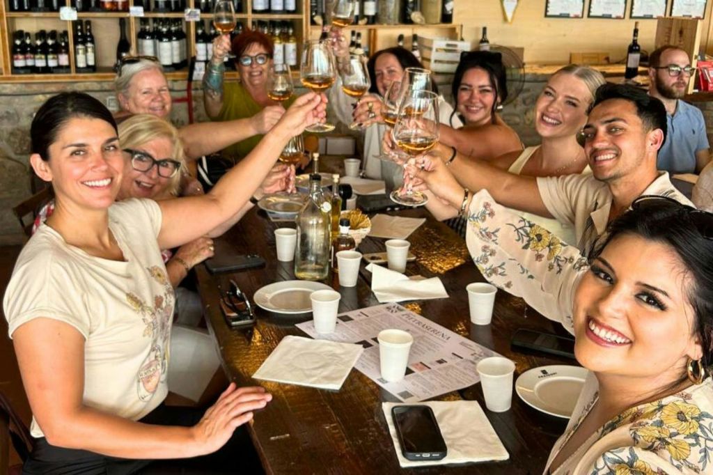 한 무리의 사람들이 레스토랑의 테이블에 앉아 안경을 들고 웃으며 함께 축하하고 있습니다.