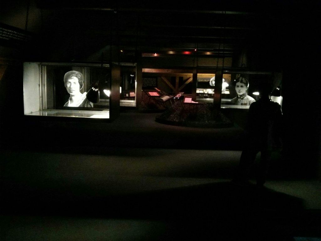 흑백 역사 사진과 스탠드에 다양한 정보 디스플레이가 있는 조명이 희미한 박물관 전시회입니다.