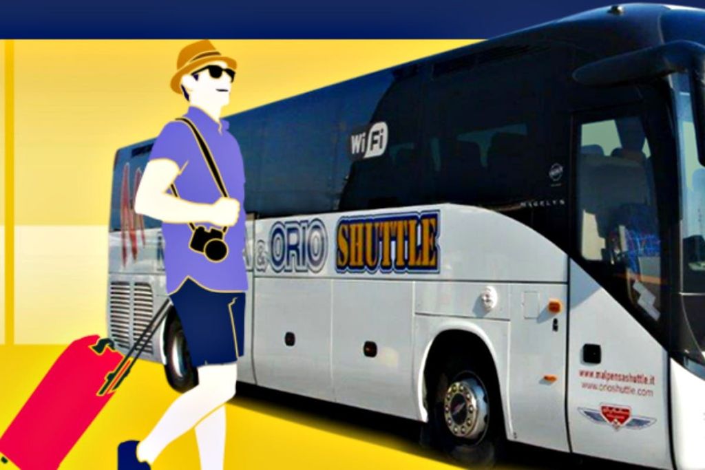 '오리오 셔틀' 이라고 적힌 셔틀버스 앞에서 빨간색 여행 가방을 들고 걷는 여름 복장을 한 사람.