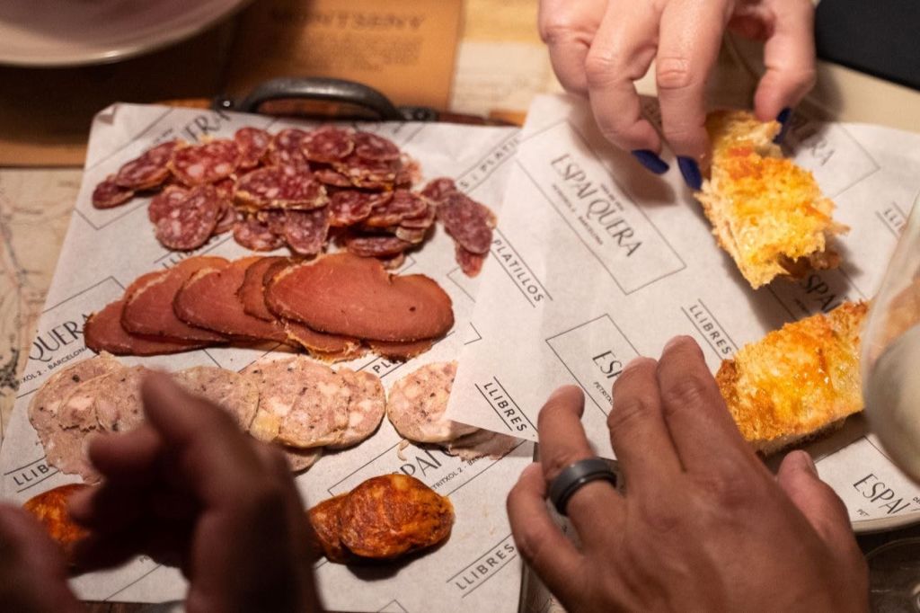 얇게 썬 경화 고기와 빵을 손에 들고 각인된 종이로 늘어선 나무 보드에 손을 뻗습니다.