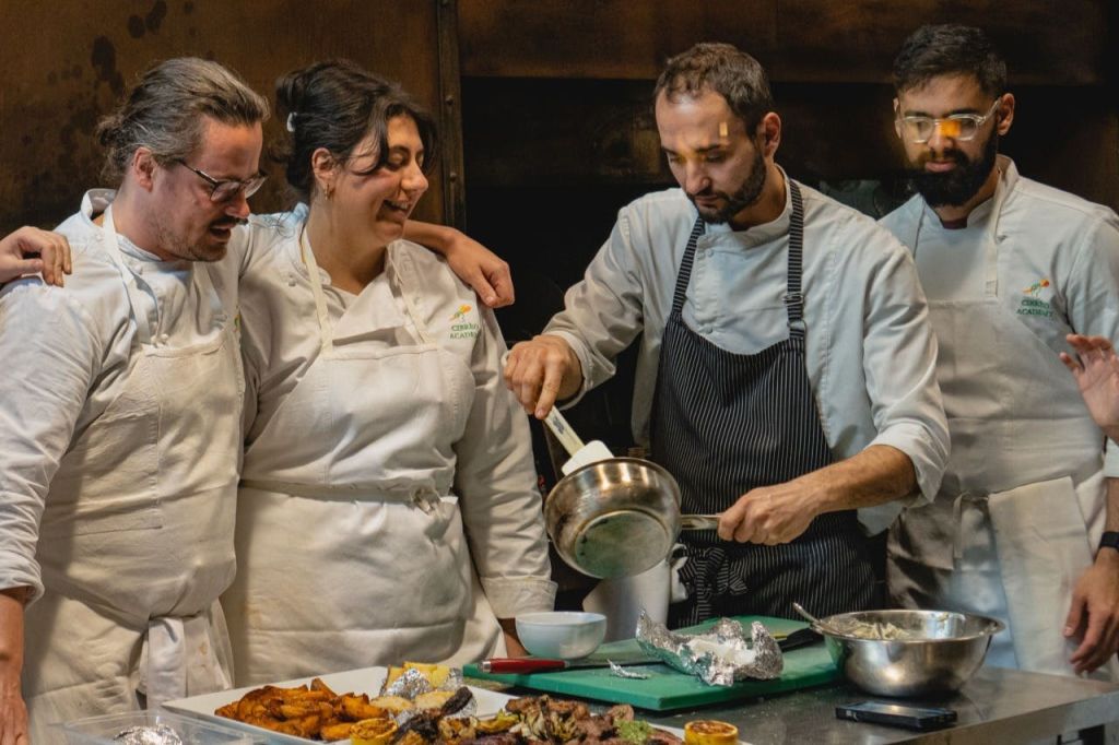 흰색 유니폼과 앞치마를 입은 셰프는 전문 주방에서 음식을 준비하고 접시로 만듭니다.