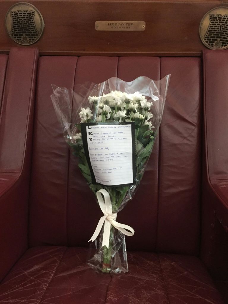 빨간색 쿠션 시트에 놓인 메모가 있는 비닐로 감싼 흰색 꽃다발.