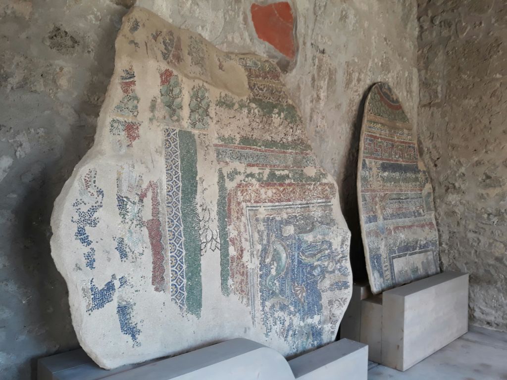 희미하고 풍화된 화려한 무늬가 돌담에 기댄 두 개의 커다란 고대 석판.