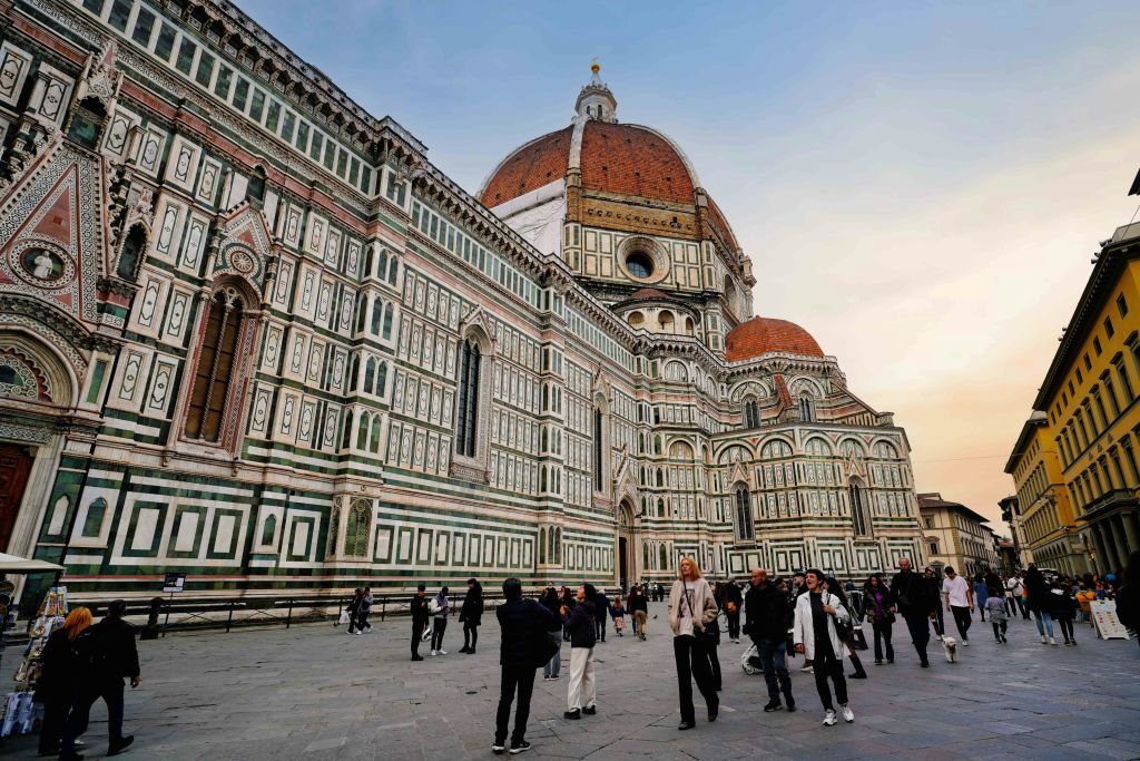 정교한 외관과 맑은 하늘 아래 커다란 돔이 있는 피렌체 대성당 앞을 걷는 사람들.