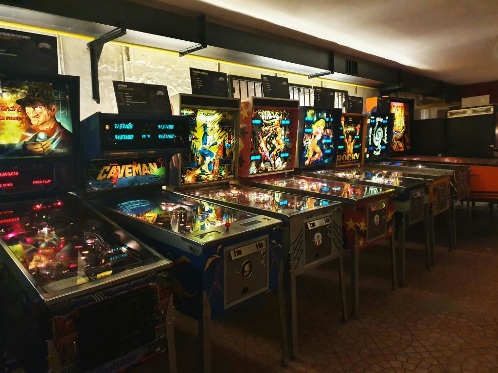 조명이 희미한 아케이드에서 화려한 빈티지 핀볼 머신이 조명을 받고 있습니다.