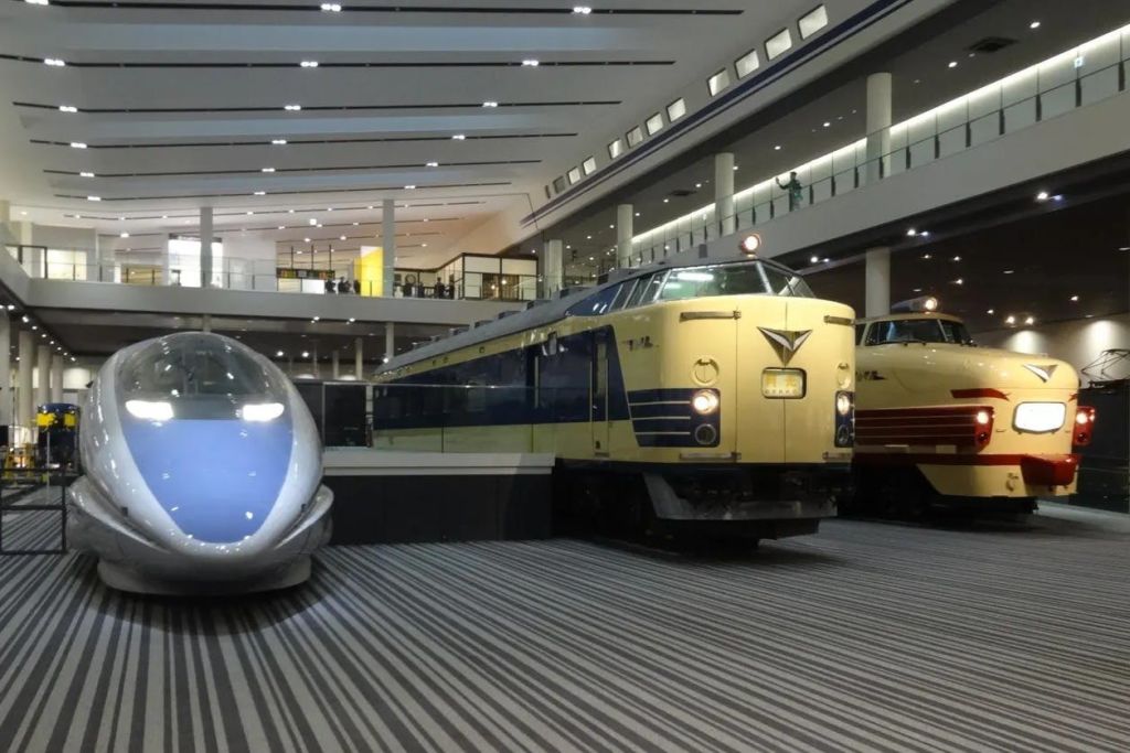 파란색과 흰색 열차, 노란색 열차 등 빈티지 열차가 전시된 박물관 전시관이 실내에 전시되어 있습니다.