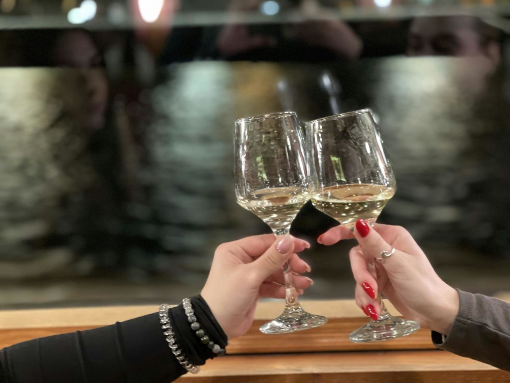 바닷가 배경이 흐릿한 두 손이 와인잔을 쥐고 있습니다.