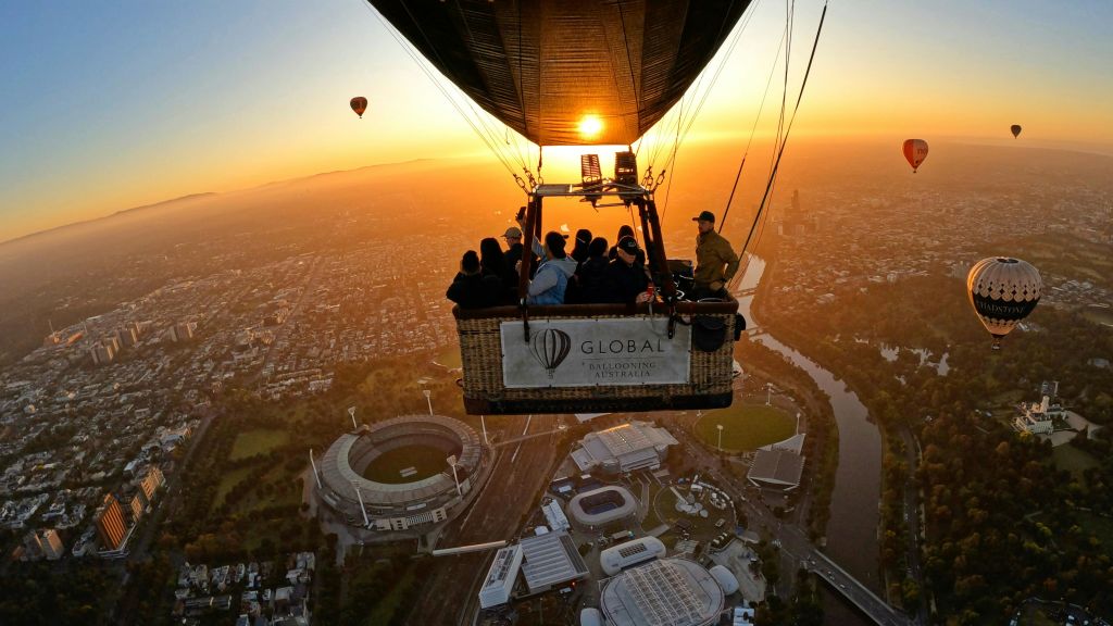 경기장, 강, 일출에 보이는 또 다른 풍선이 있는 도시 풍경 위의 열기구에 탄 사람들.