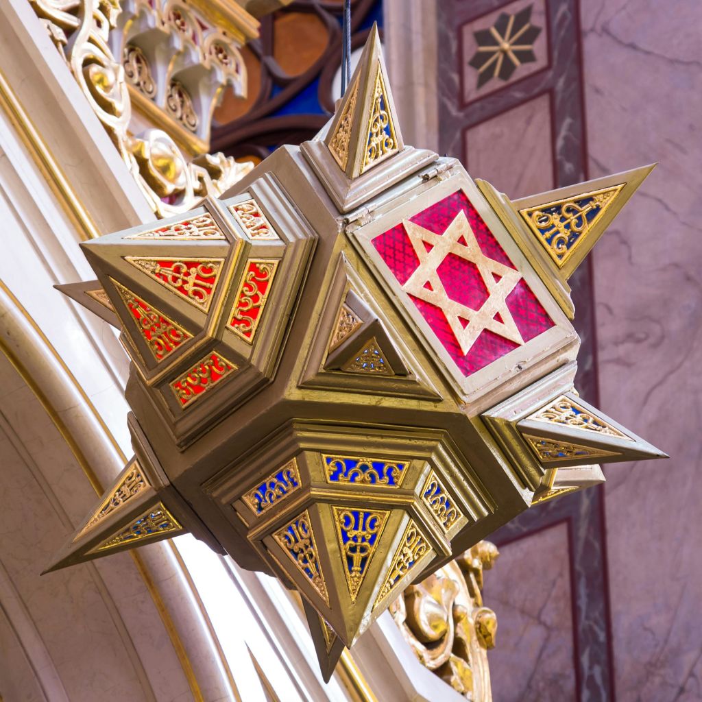 빨간색, 파란색, 노란색 패턴의 패널이 있는 화려한 별 모양의 랜턴으로, 실내에 매달려 있는 다윗의 별이 특징입니다.