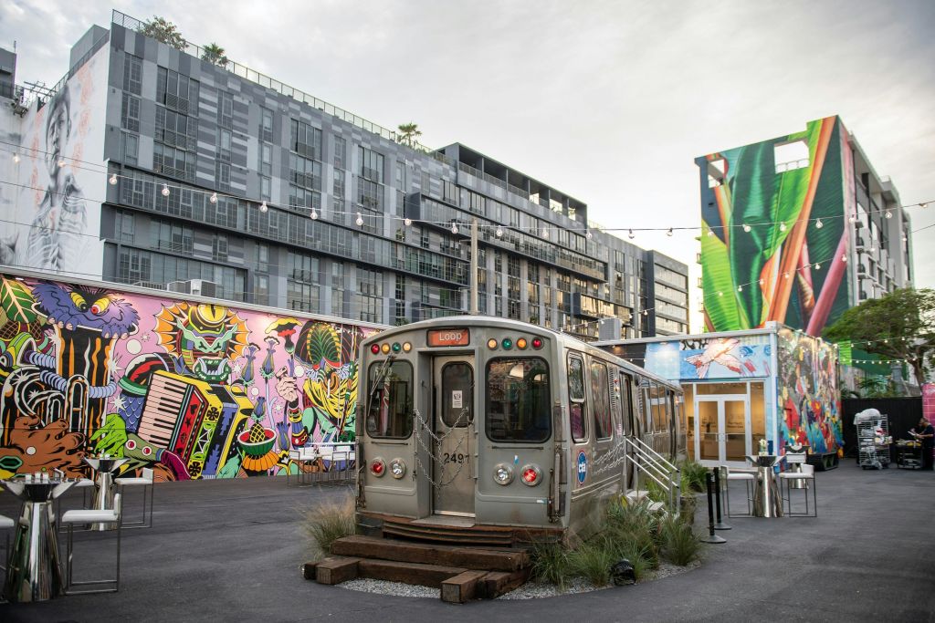 활기찬 벽화로 둘러싸인 다이너로 재탄생한 해체된 지하철 차량은 아파트를 배경으로 한 도심 안뜰에 있습니다.