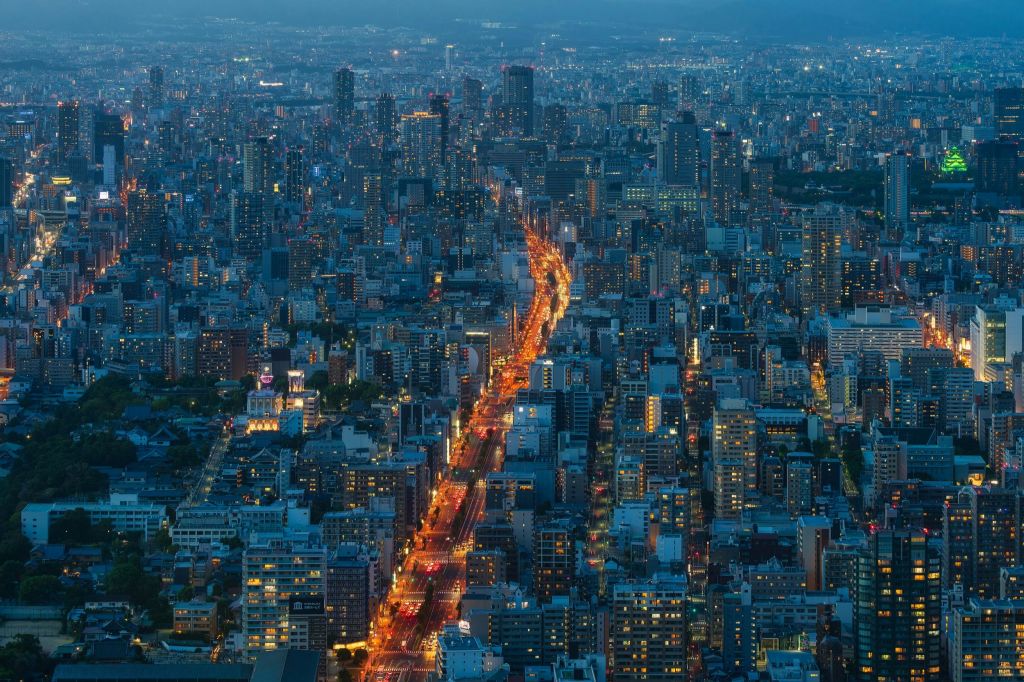 해질 녘에 조명이 켜진 거리와 빽빽한 고층 건물이 있는 도시의 공중 전망을 감상할 수 있습니다.