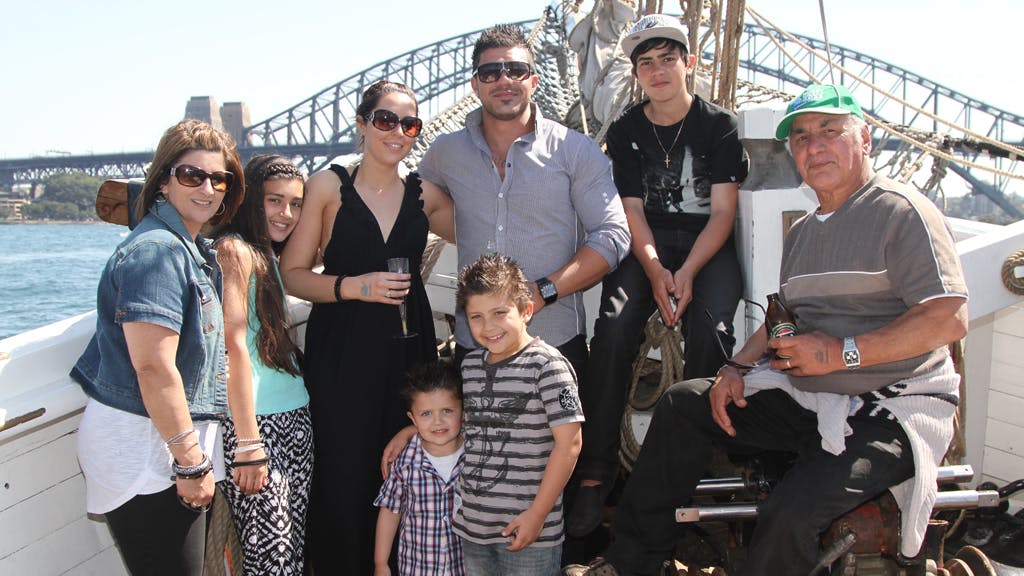 화창한 날, 보트를 타고 다리가 보이는 보트에서 미소를 짓고 포즈를 취하고 있는 7명의 일행.