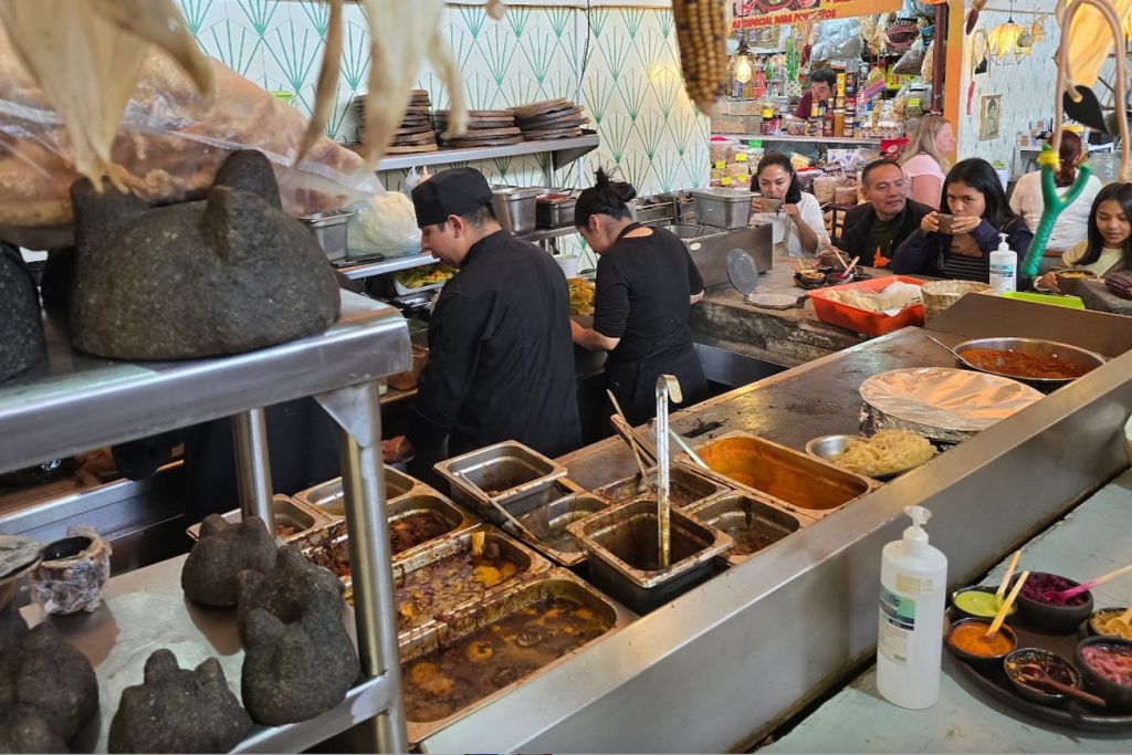 바쁜 오픈 키친의 셰프들은 고객이 카운터에 앉아 식사를 하는 동안 음식을 준비합니다. 여러 개의 푸드트레이가 보입니다.