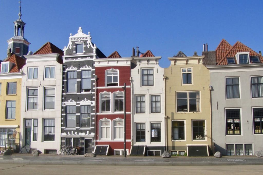 화창한 날에 화려한 외관과 화려한 지붕을 갖춘 네 개의 다채롭고 좁은 건물이 줄지어 있습니다.