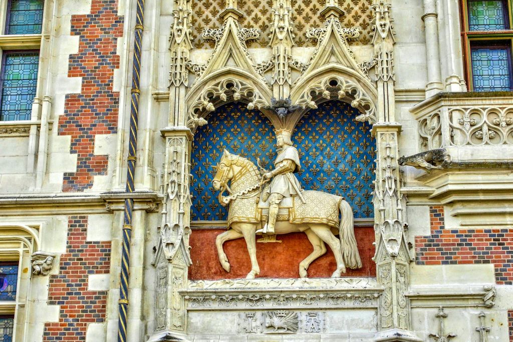 파란색 무늬를 배경으로 정교한 디테일이 돋보이는 고딕 스타일의 틈새시장에서 승마를 즐기는 남자의 화려한 석상.