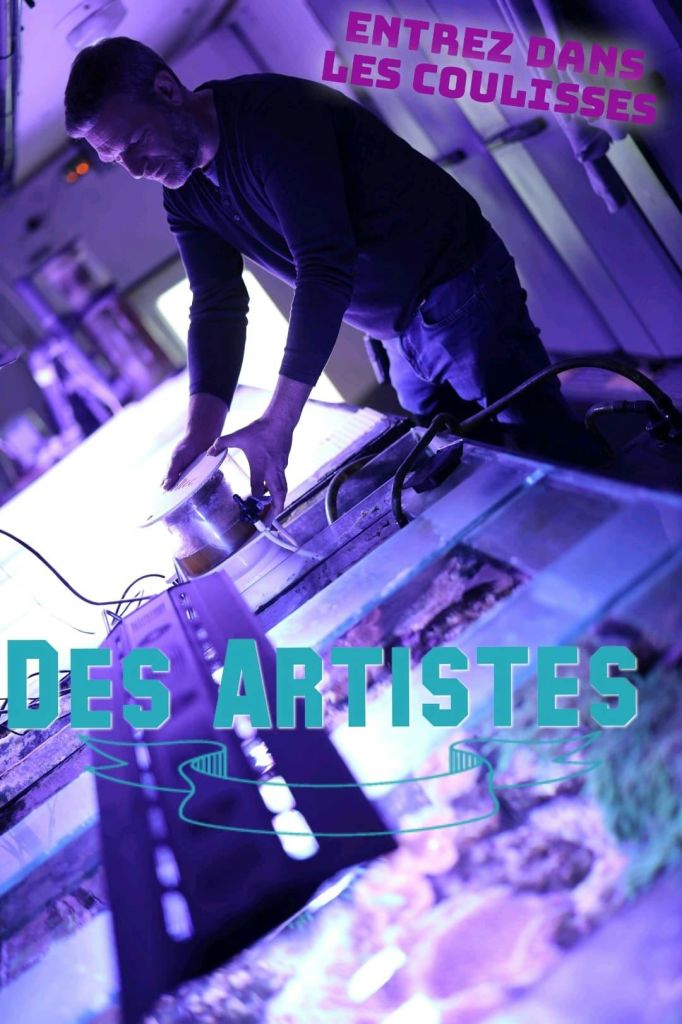 빛나는 탱크 옆의 보라색 조명 아래에서 장비를 조정하는 사람. 텍스트 오버레이에는 장식 선이 있는 "DES ARTISTES" 가 표시됩니다.