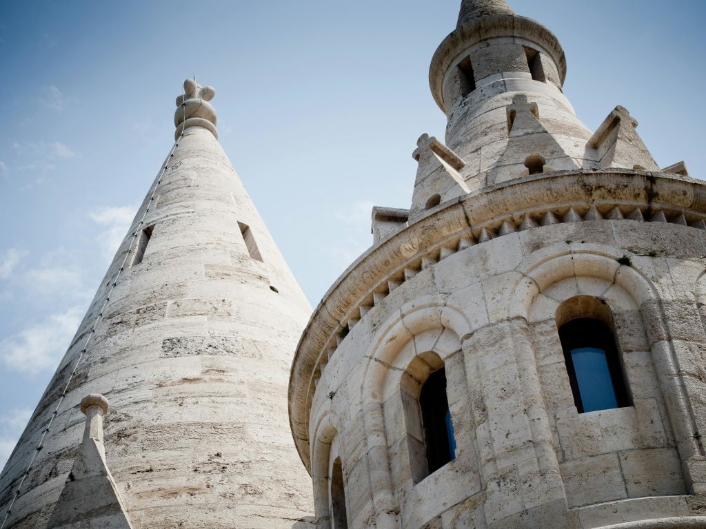 원뿔형 지붕과 아치형 창문이 있는 두 개의 석탑은 맑고 푸른 하늘을 배경으로 합니다.