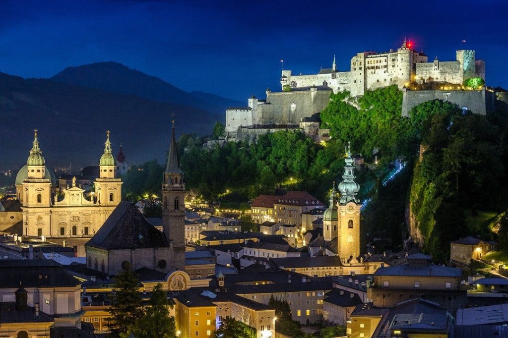 산을 배경으로 밤에는 마을의 교회 첨탑과 건물이 내려다보이는 언덕 꼭대기에 밝게 빛나는 유서 깊은 성입니다.