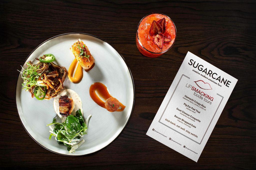 다양한 아이템이 담긴 고급 음식 한 접시와 빨간 음료, 어두운 나무 테이블에 놓인 메뉴.