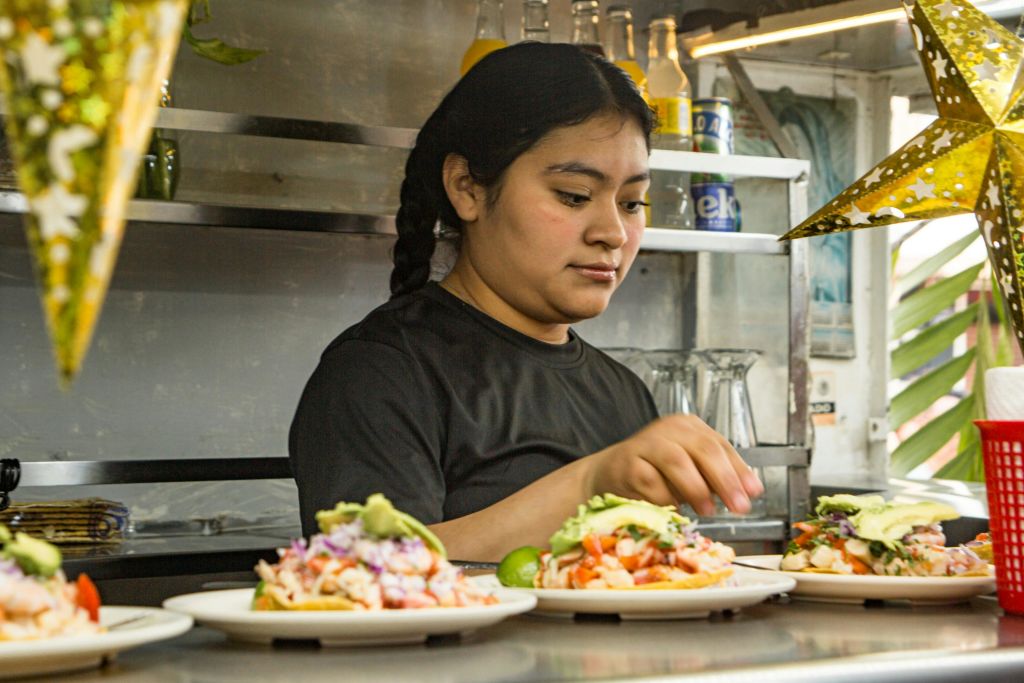음식 가판대에서 화려한 토핑과 장식품을 포함한 음식 접시를 준비하는 사람.