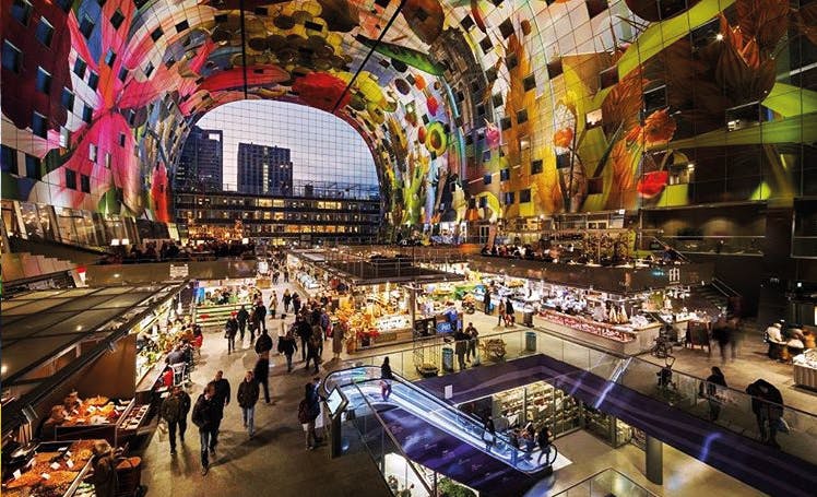 아치형 천장에 다채로운 예술품, 음식점, 쇼핑객, 에스컬레이터가 있는 번잡한 실내 시장.