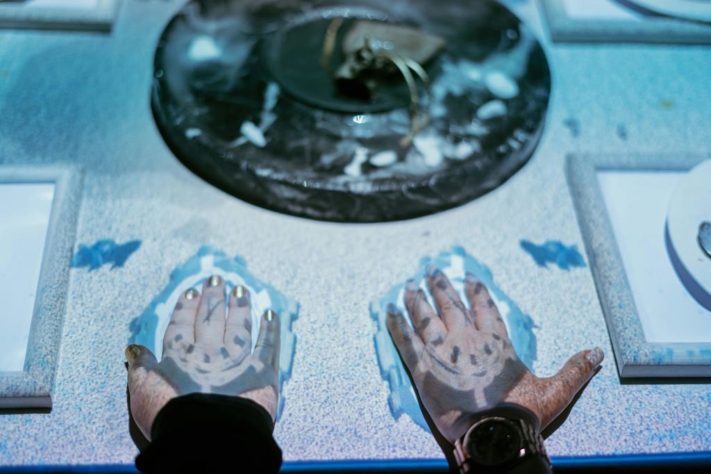 세븐 페인팅스 몰입형 다이닝 쇼에서 게스트는 테이블의 예상치와 상호작용하고 있습니다.