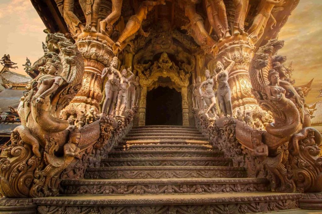 어두운 아치형 입구로 이어지는 세부 석상으로 장식된 정교하게 조각된 나무 계단.