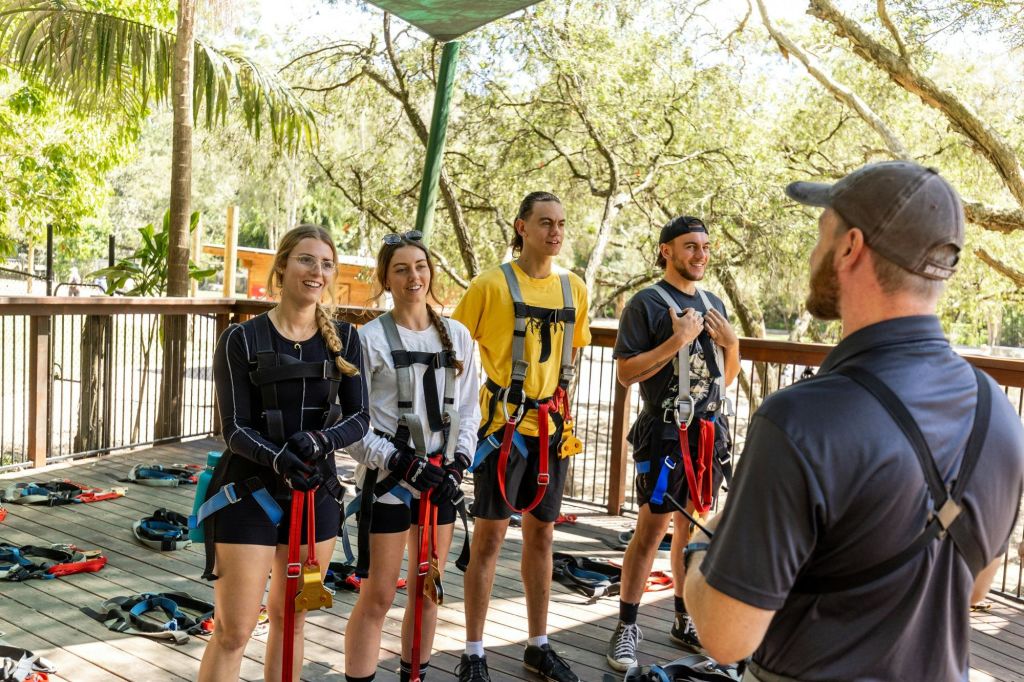 나무를 배경으로 야외에서 강사의 말을 들으며 나무 데크에 네 명이 서 있습니다.