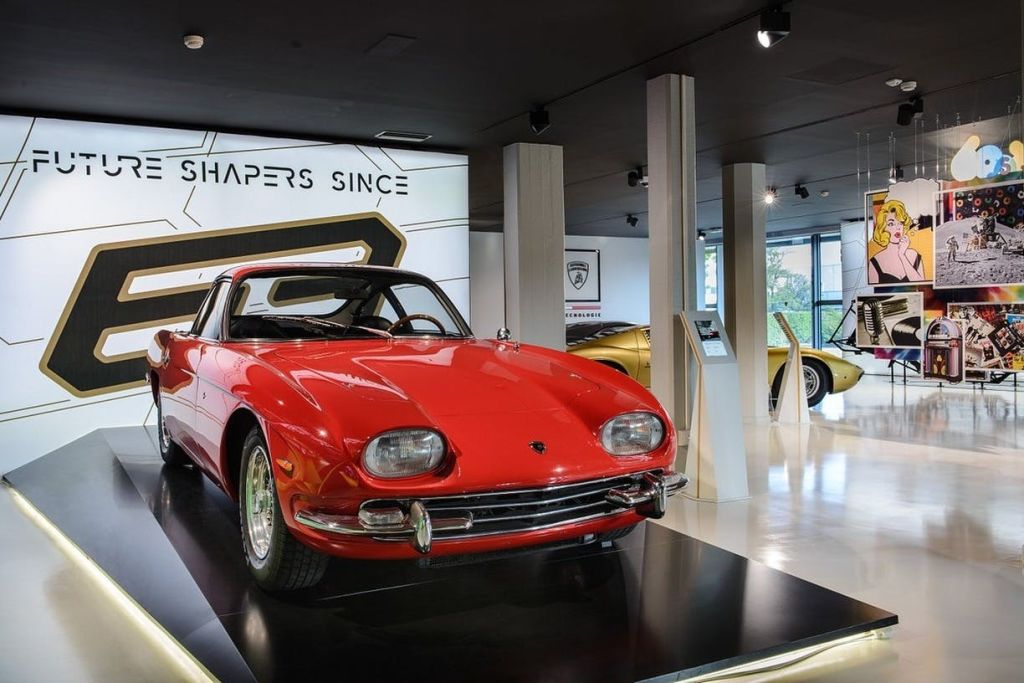 세련된 조명과 간판을 배경으로 현대적인 쇼룸에 빨간색 빈티지 자동차가 전시되어 있습니다.