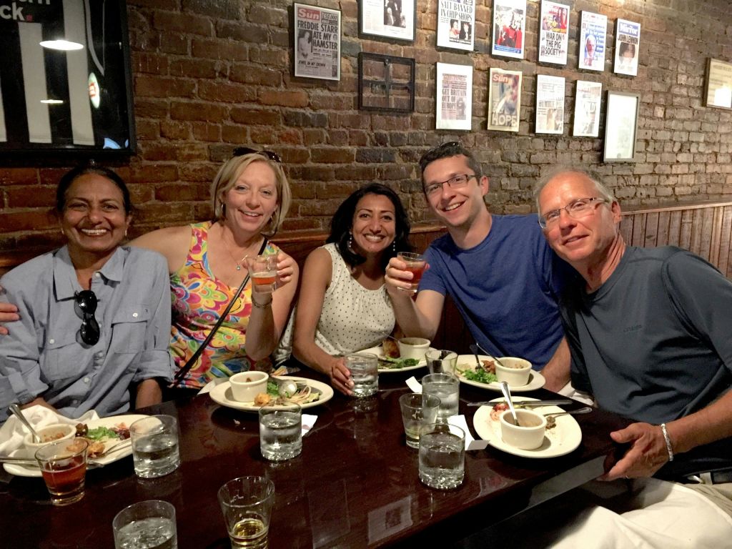 벽돌 벽 배경의 레스토랑 테이블에서 미소를 짓고 음식과 음료를 즐기는 사람들의 모임.