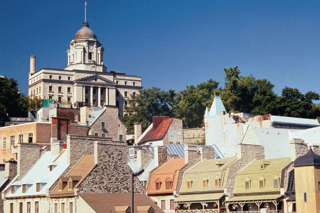 돔형 지붕이 있는 역사적인 건물에서는 맑고 푸른 하늘 아래 나무로 둘러싸인 화려한 돌 지붕의 집들이 내려다보입니다.