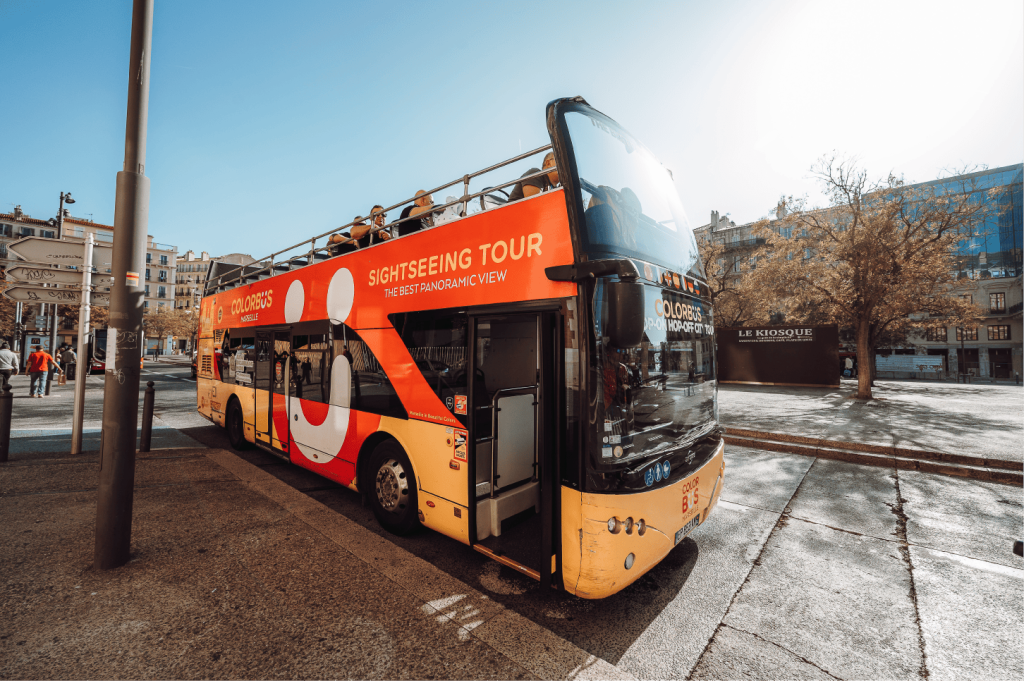 화창한 날 정박지 근처에 주차된 빨간색 2층 관광 투어 버스에는 'Colorbus Marseille' 이라는 라벨이 있습니다.