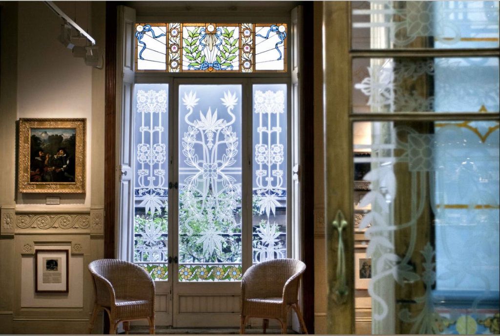 정교한 꽃무늬 디자인의 나무 프레임 유리문, 상단의 스테인드글라스, 매력적인 실내 분위기의 고리버들 의자 2개.