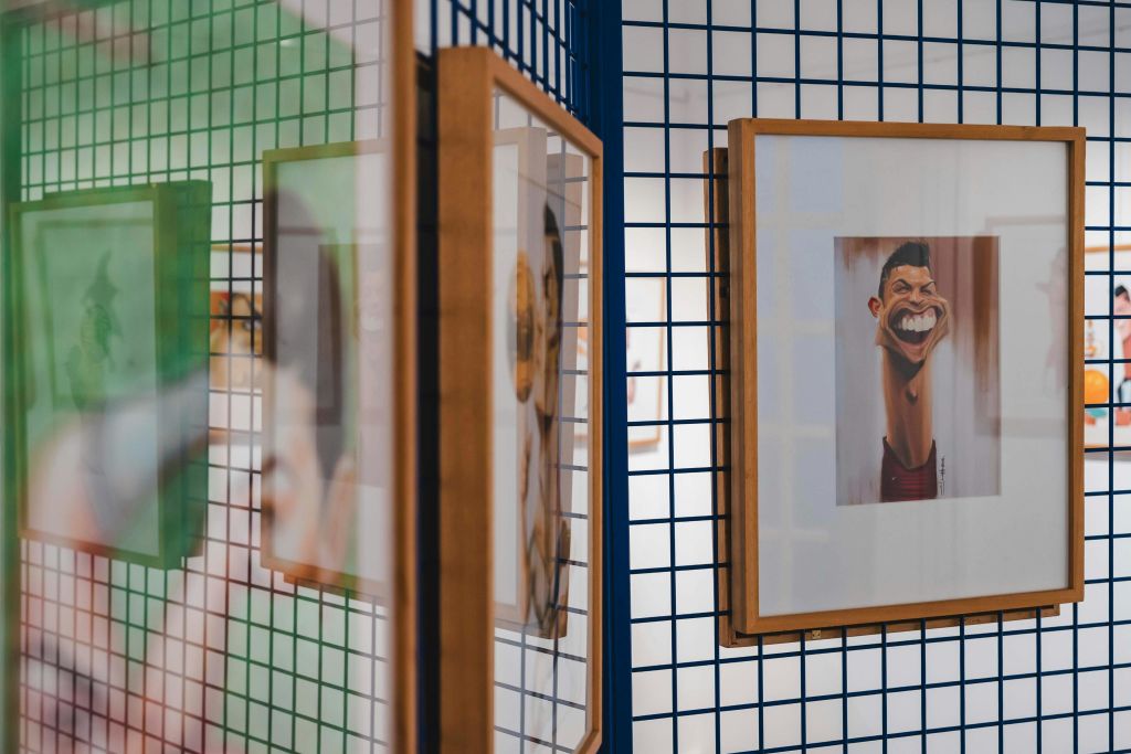 두 개의 액자 캐리커처 작품이 아트 갤러리의 파란색 격자 벽에 표시됩니다.