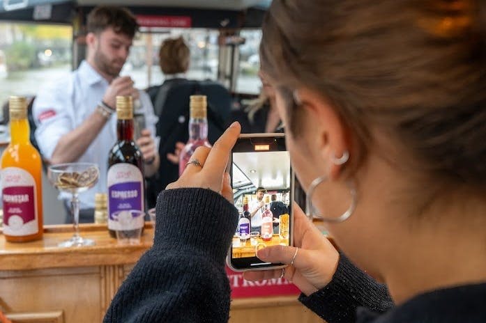 바에서 칵테일을 만드는 모습을 동영상으로 촬영한 여성