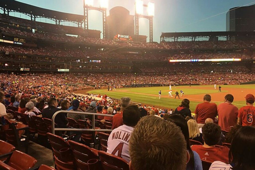 저녁에 경기장에서 펼쳐지는 생동감 넘치는 야구 경기로, 전경에는 팬들이 앉아 있고 경기장에는 선수들이 앉아 있습니다.