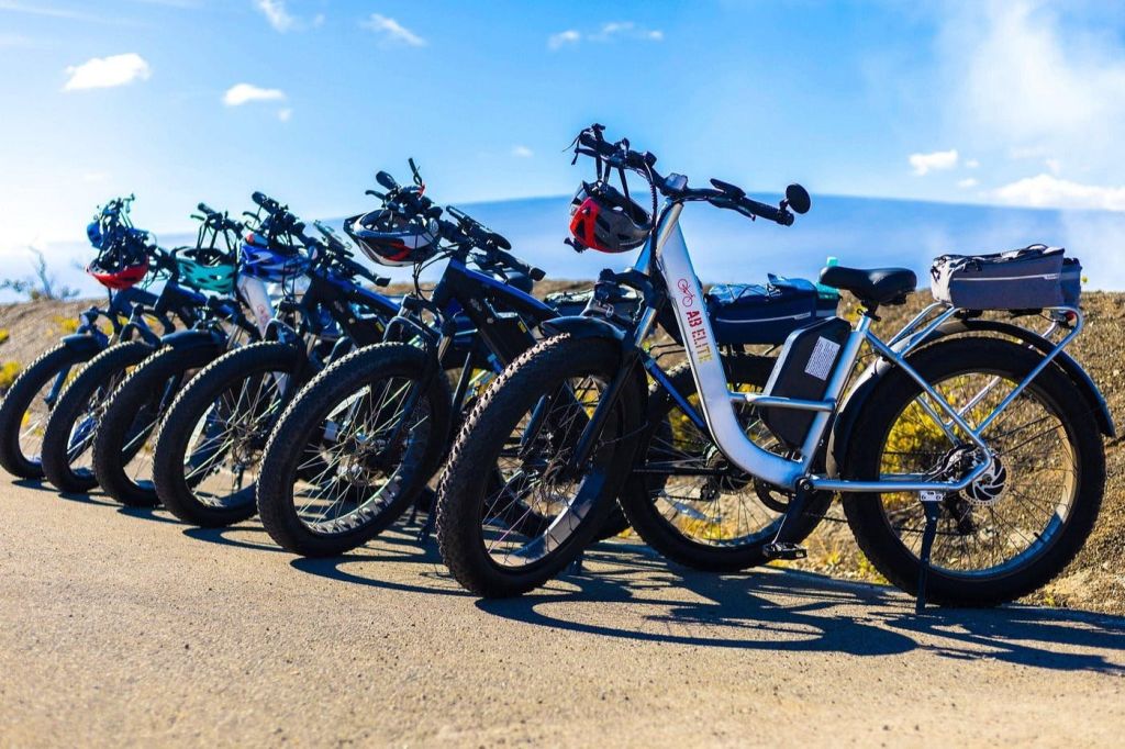 파란 하늘 아래 포장된 표면에 대형 타이어가 달린 전기 자전거 4대가 주차되어 있습니다.