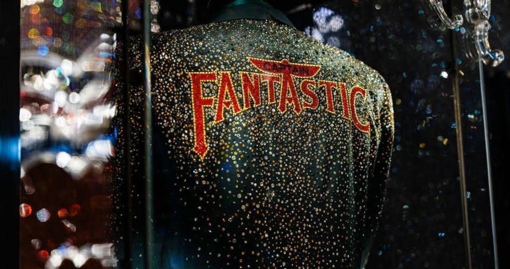 반짝이는 장식으로 덮인 재킷의 클로즈업으로 뒷면에 대담한 빨간색 글씨로 "FANTASTIC" 이라는 단어가 쓰여 있습니다.