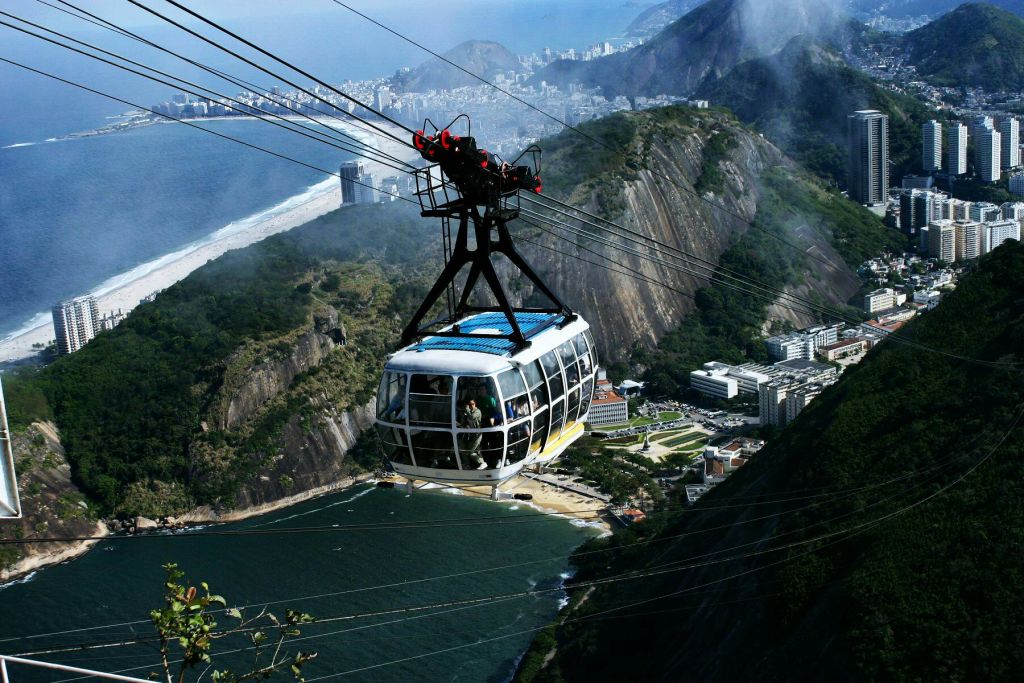 산과 건물, 바다를 배경으로 해안 도시 위에 케이블카가 매달려 있습니다.