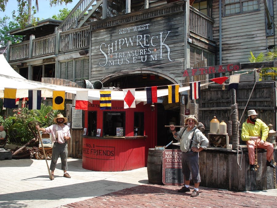 키 웨스트 난파선 보물 박물관 (Key West Shipwreck Treasures Museum) 바깥에는 역사적인 복장을 한 두 남자가 머리 위로 해상 깃발을 들고 서 있습니다.