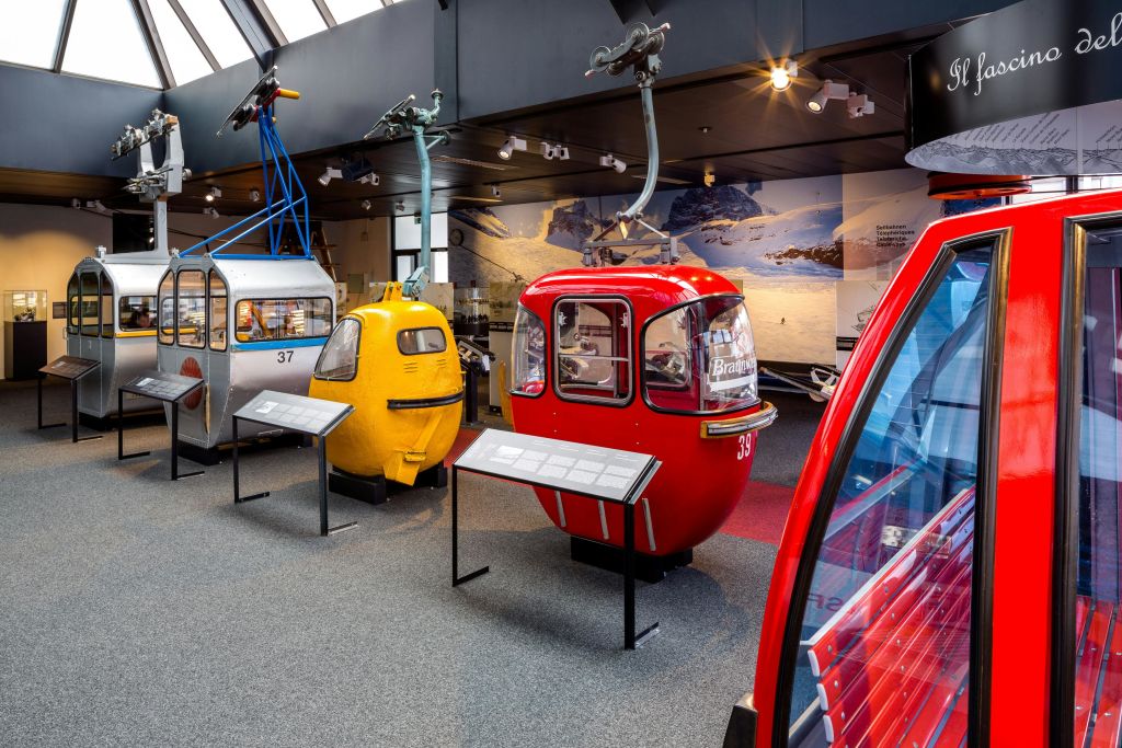 파란색, 노란색, 빨간색 통나무집 등 다양한 빈티지 곤돌라 리프트 통나무집이 박물관에 전시되어 있습니다.