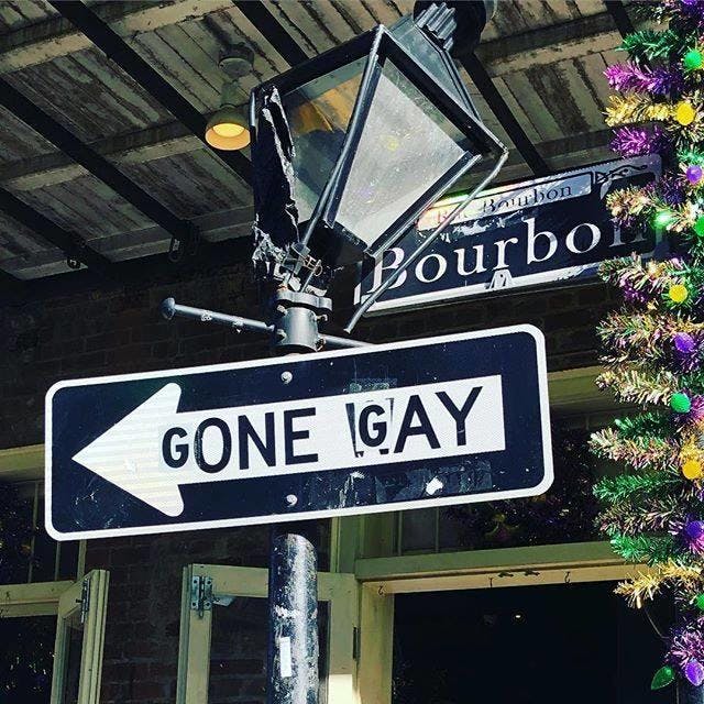 버번 스트리트의 부서진 램프와 축제 장식 옆에 'Gone Gay' 라고 적힌 유머러스한 거리 표지판이 있습니다.