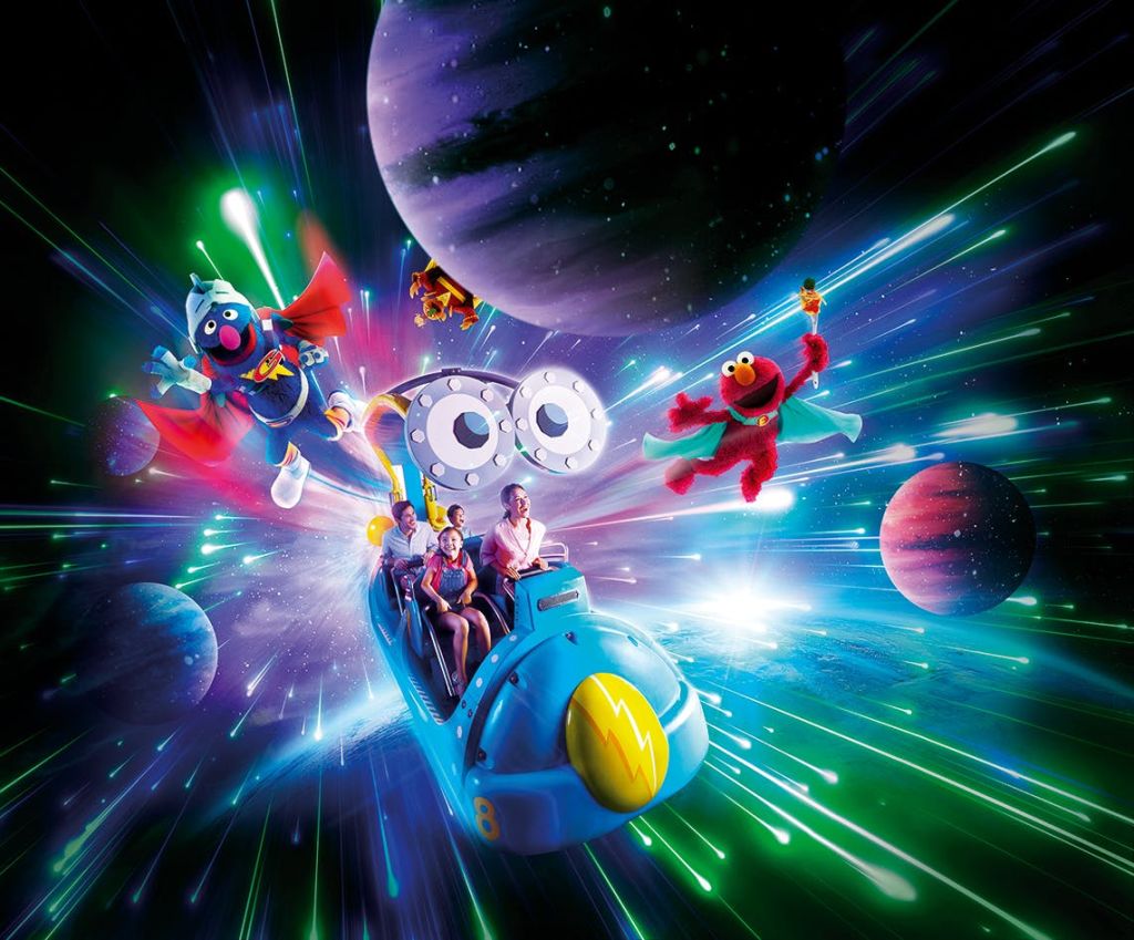 다채로운 우주 배경을 배경으로 움직이는 캐릭터와 행성으로 둘러싸인 푸른 우주를 테마로 한 라이드를 즐기는 사람들.